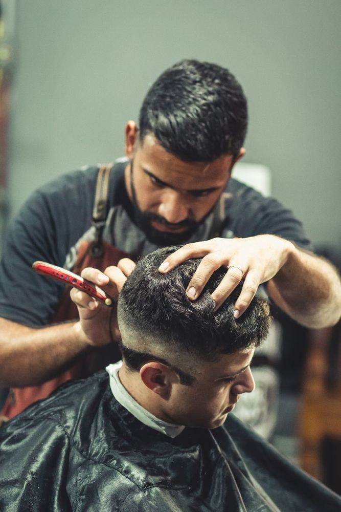 Barber giving a man a short fade haircut